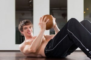 Ein Junge trainiert Sit-Ups mit einem Medizinball