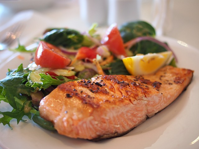 Ein gebratenes Stück Lachs auf einem Teller mit ein wenig Salat als Beilage