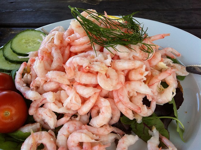 Ein großer Haufen gekochter Shrimps auf einem Teller garniert mit ein paar Kräutern