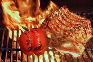 Ein Steak und eine Tomate auf einem brennenden Grill