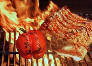 Ein Steak und eine Tomate auf einem brennenden Grill