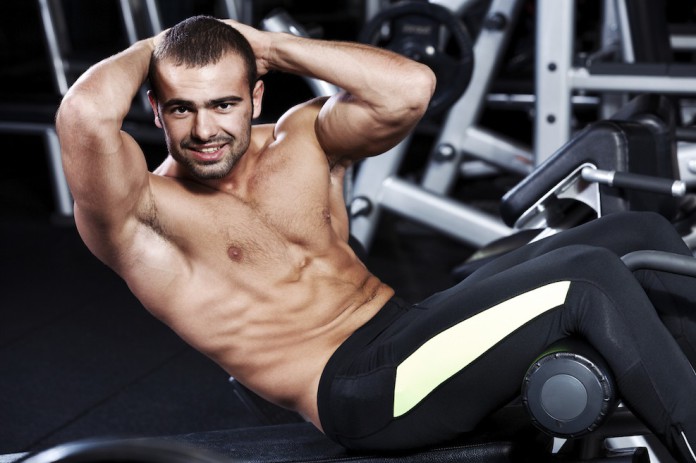 Sportler trainiert seine seitlichen Bauchmuskeln mit Cross-Crunches