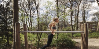 Sportlerin trainiert Dips zur Brust auf einem Barren