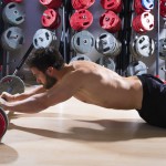 Sportler im Fitnesscenter rollt auf einer Langhantel