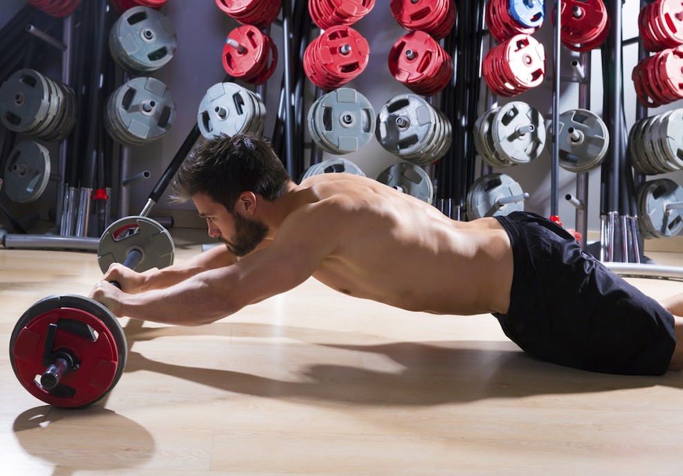 Sportler im Fitnesscenter rollt auf einer Langhantel