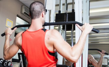 Sportler trainiert am Latzug seine Brustmuskeln