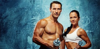 Ein trainierter Mann und eine fitte Frau jeweils mit einer Hantel in der Hand