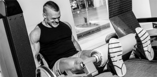 Ein Bodybuilder hebt ein Gewicht mit letzter Kraft und schmerzverzerrtem Gesicht