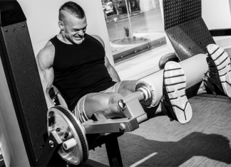 Ein Bodybuilder hebt ein Gewicht mit letzter Kraft und schmerzverzerrtem Gesicht
