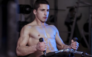 Sportler trainiert an einer Zugmaschine rudern.