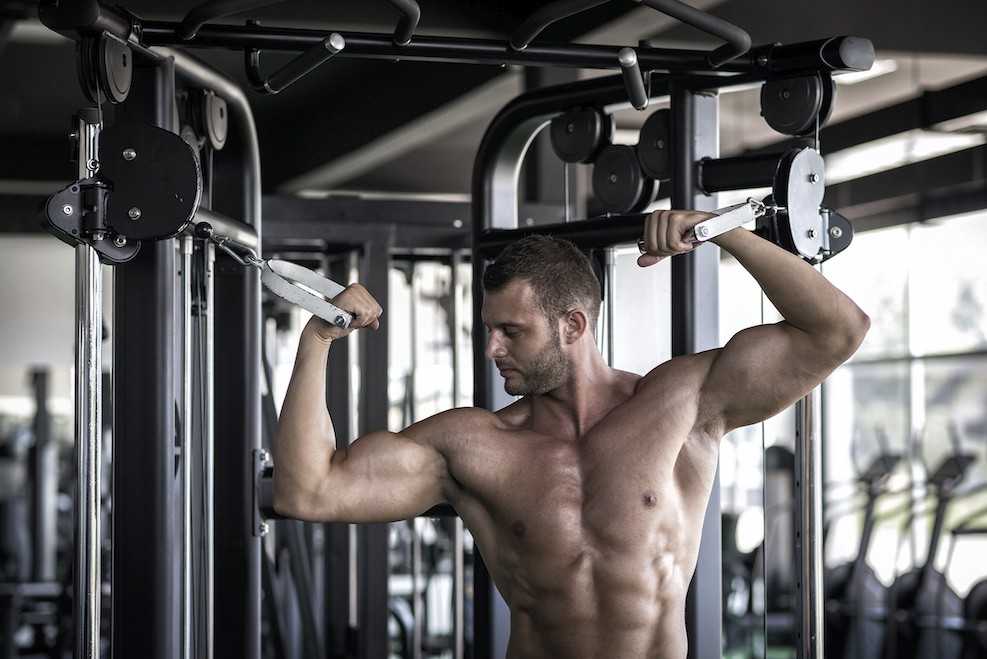 Sportler trainiert Scottcurls an einer Kabelzug-Maschine