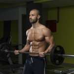 Sportler trainiert mit der Langhantel den Unterarm-Curl