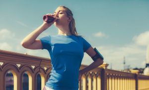 Eine Frau im sportlichen Outfit trinkt einen Eiweißshake