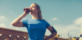 Eine Frau im sportlichen Outfit trinkt einen Eiweißshake