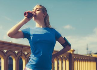 Eine Frau im sportlichen Outfit trinkt einen Eiweißshake